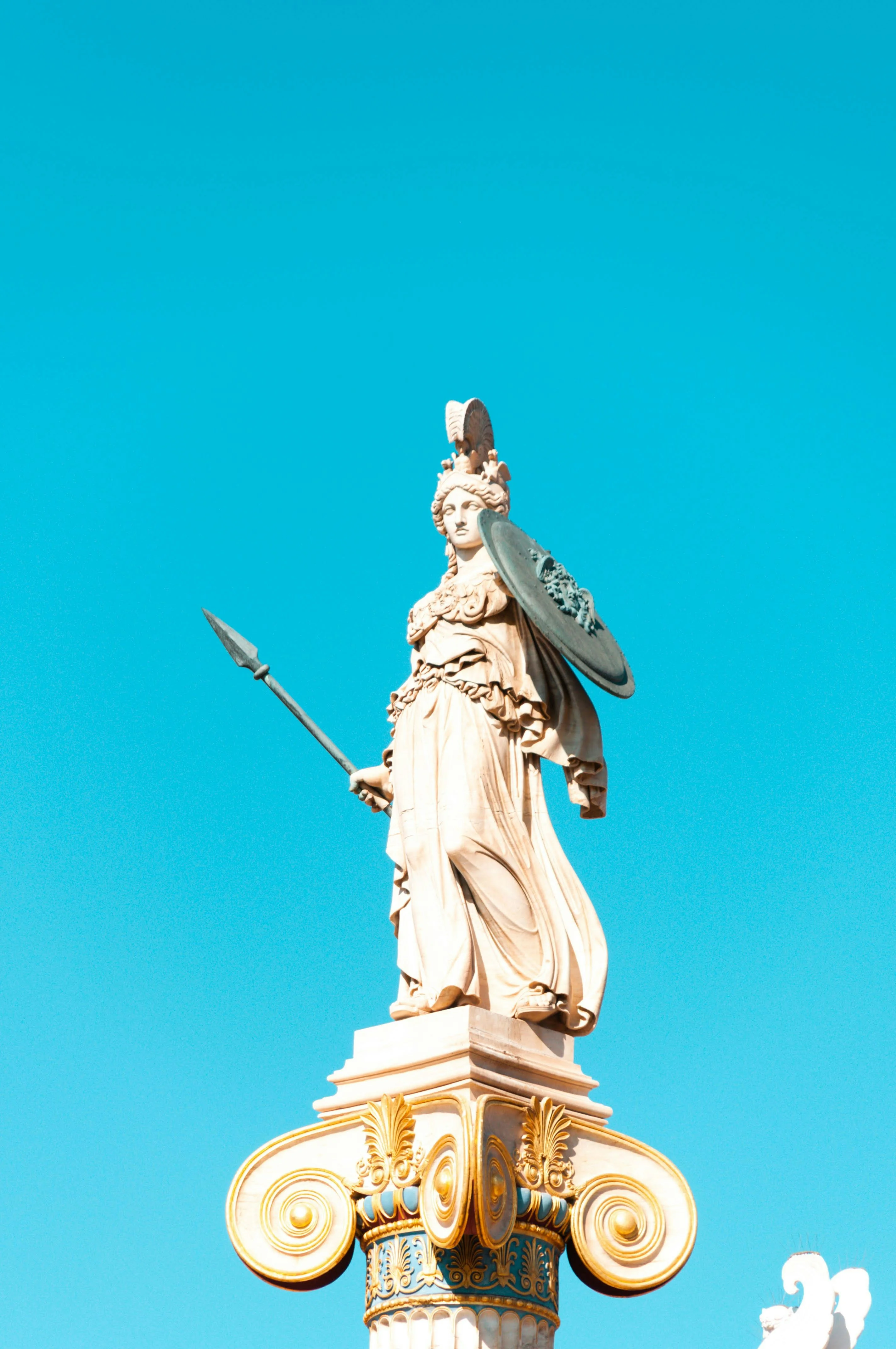 Classical marble statue looking toward a clear blue sky, representing knowledge and architecture.